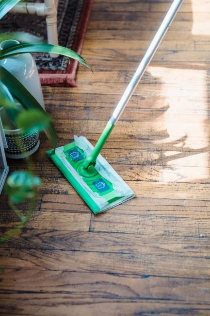 A professional cleaner in protective gear vacuuming the floor in a modern living room.